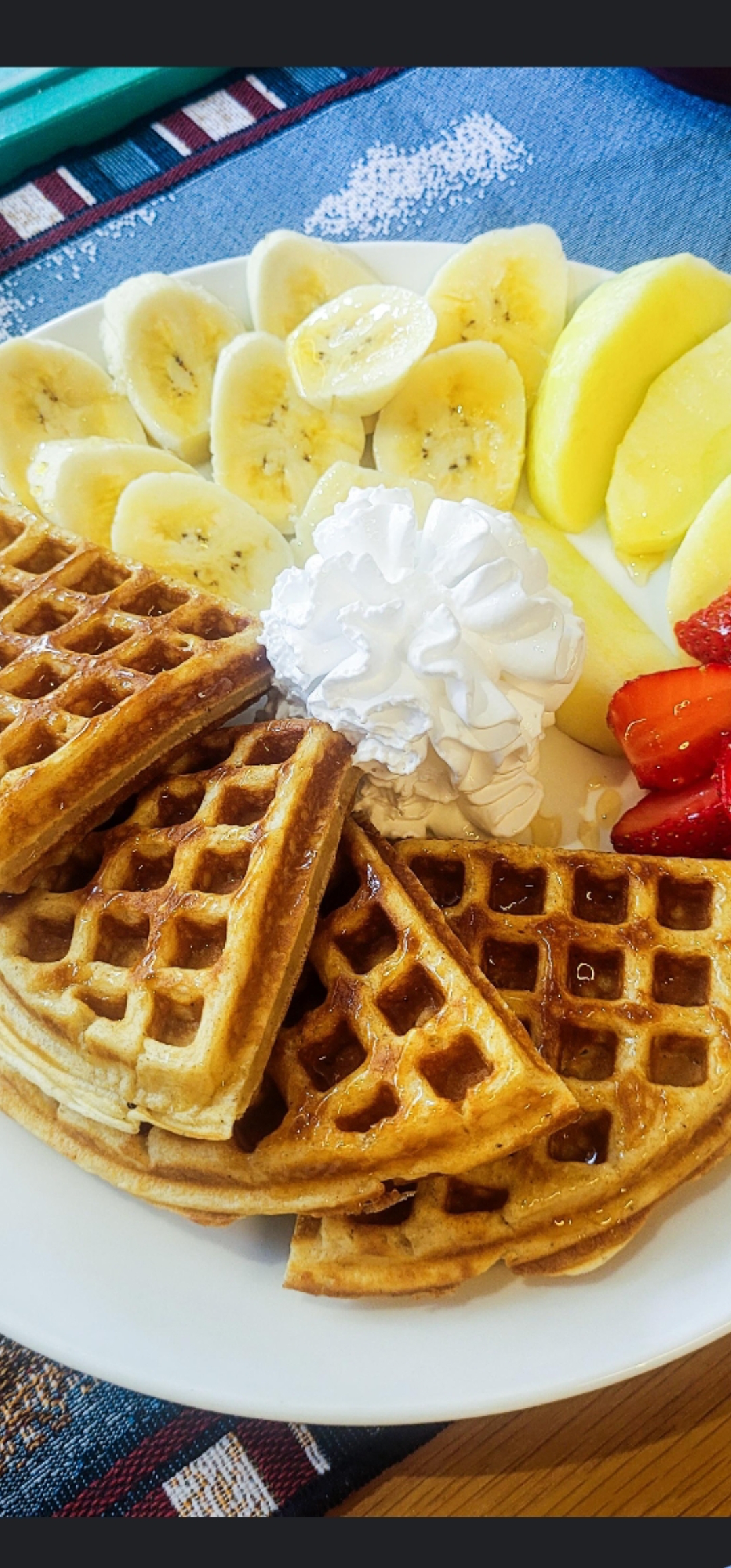 Waffles topped with banana, apple, strawberry and whipped cream